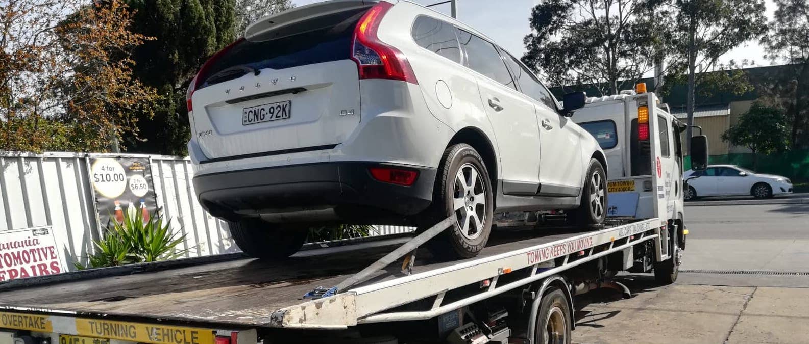 Car getting towed by a tilt tray truck in Sydney.