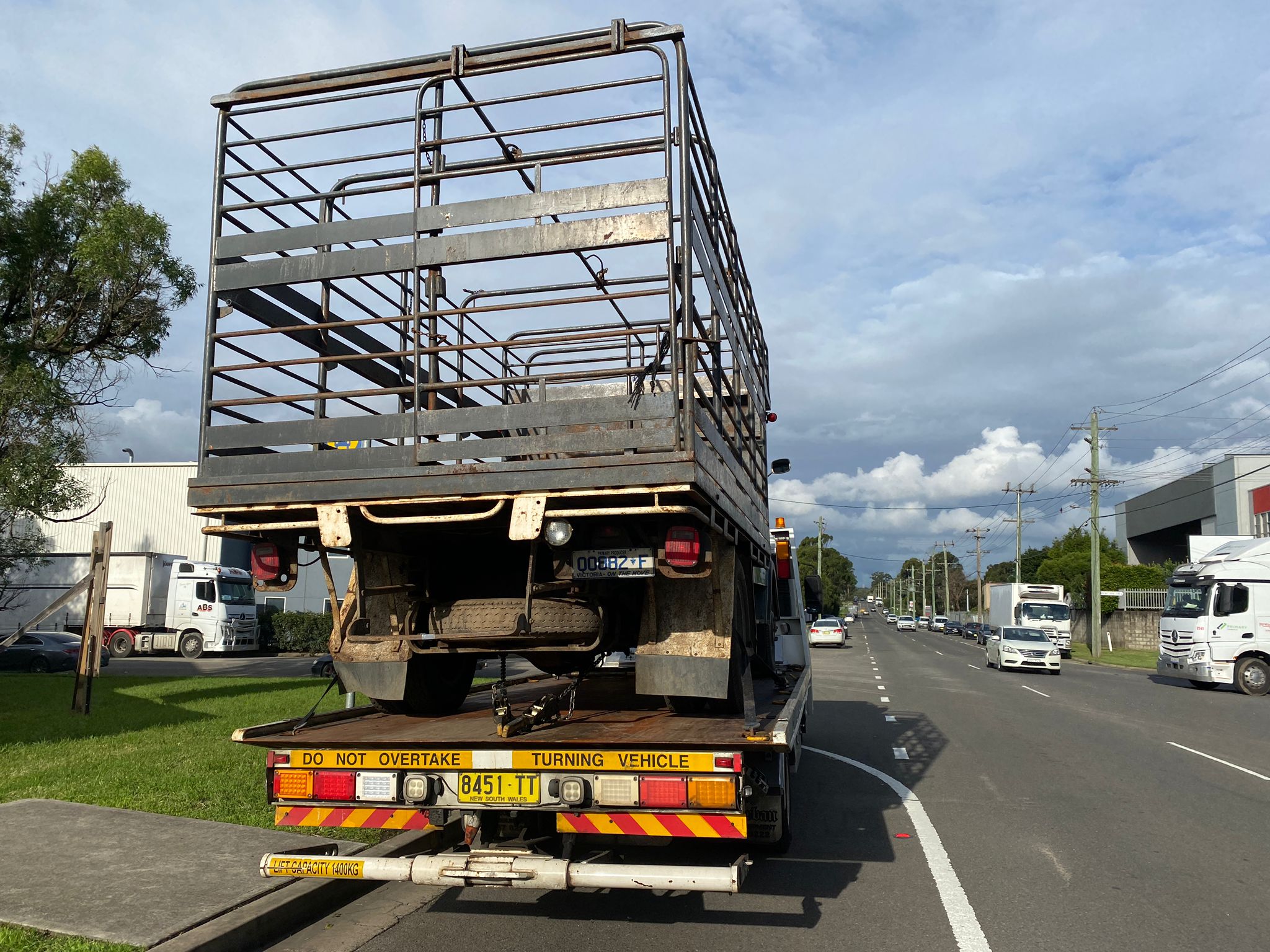 A farm truck being towed by a tow truck.