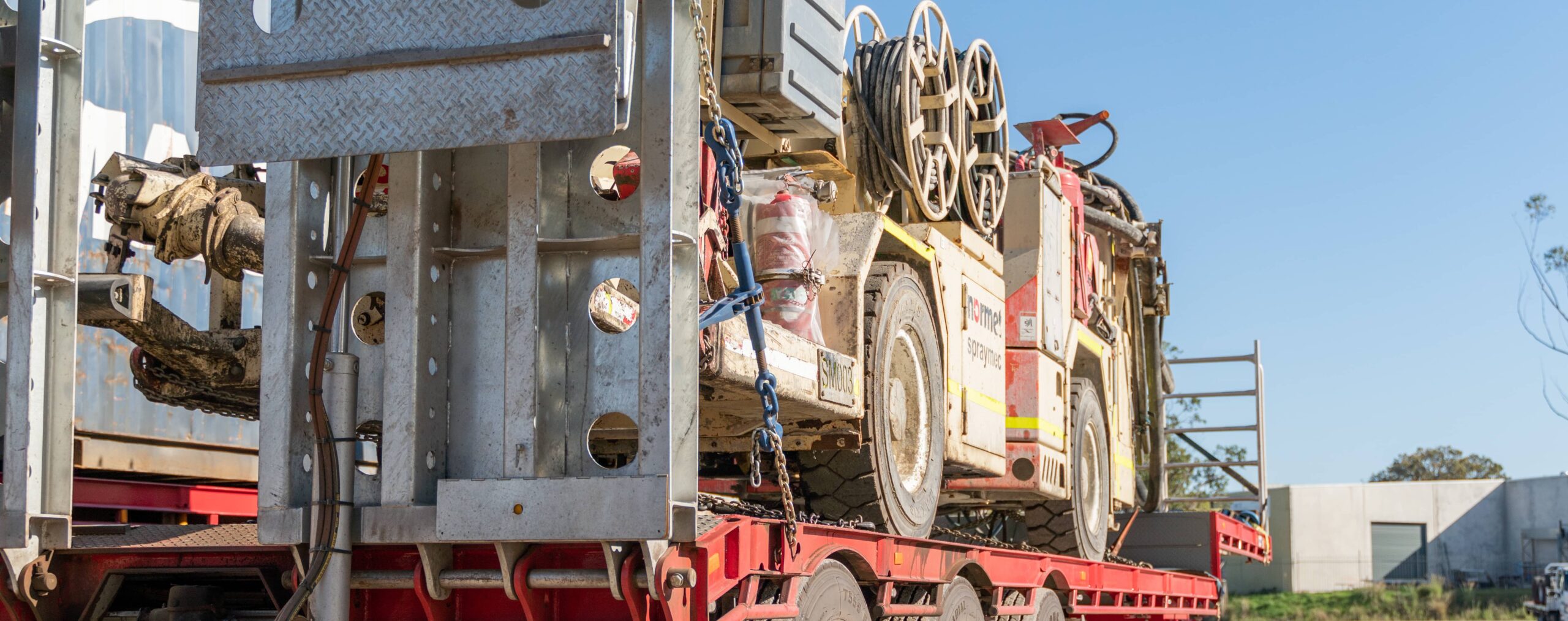 A heavy machine being transported by a large truck.