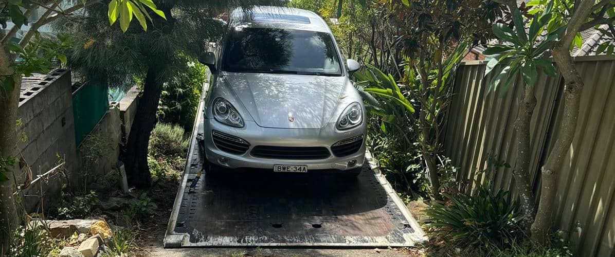 A luxury car getting towing in a Sydney driveway by a tow truck. 