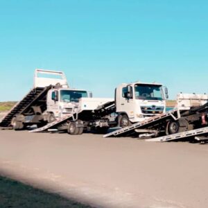 Tilt tray trucks towing each other for a photo in Sydney.