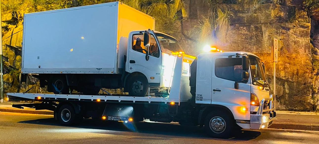 A tow truck towing a truck at night in Sydney.