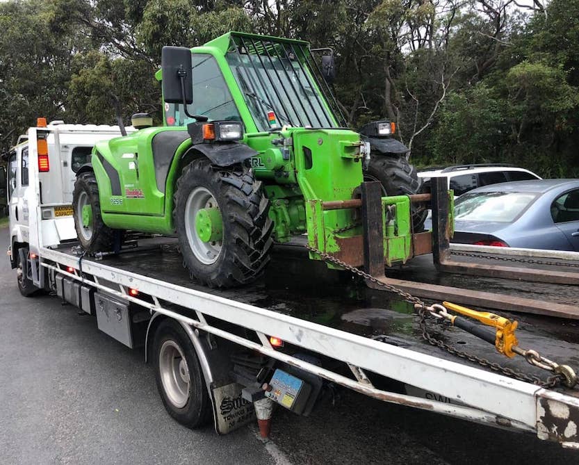 A telehandler on the back of a tow truck.