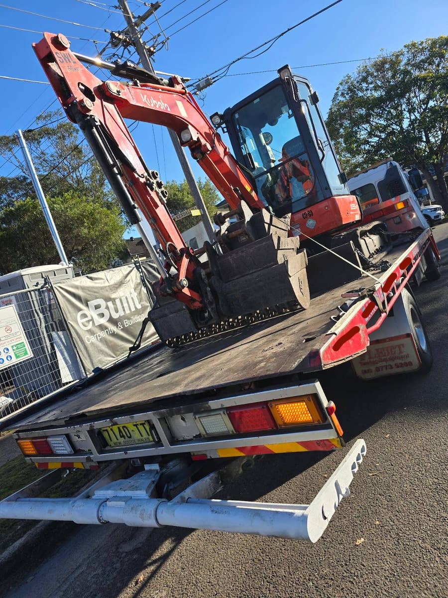 And excavator on the back of a tow truck in Sydney Austalia.